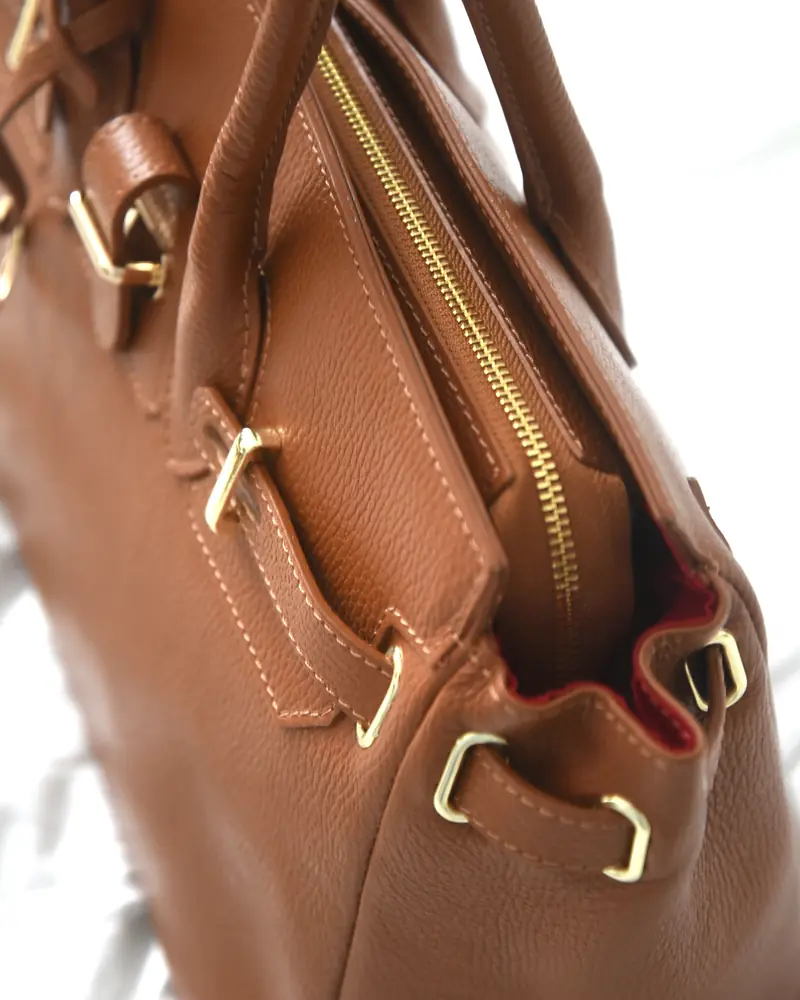 Close-up of a cognac leather bag with brass hardware