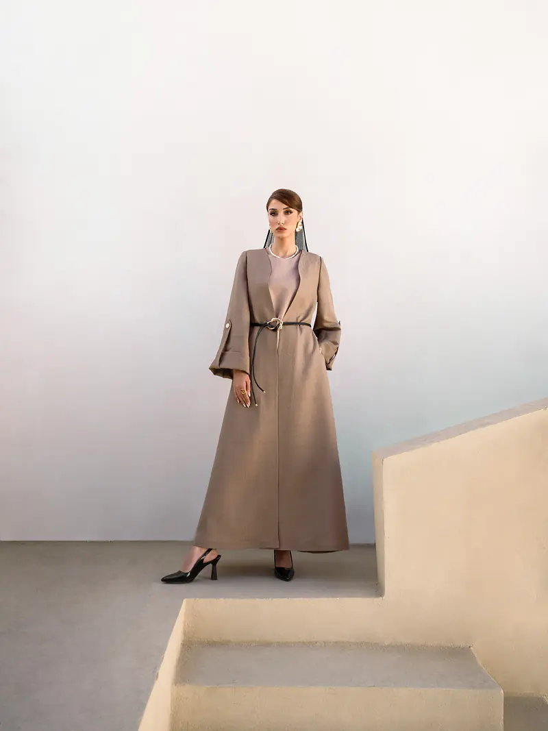 Long belted coat in sand, worn against pale stone steps