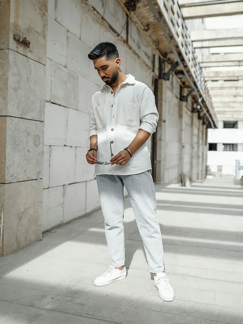 Ecru overshirt and white trousers against a sunlit stone wall