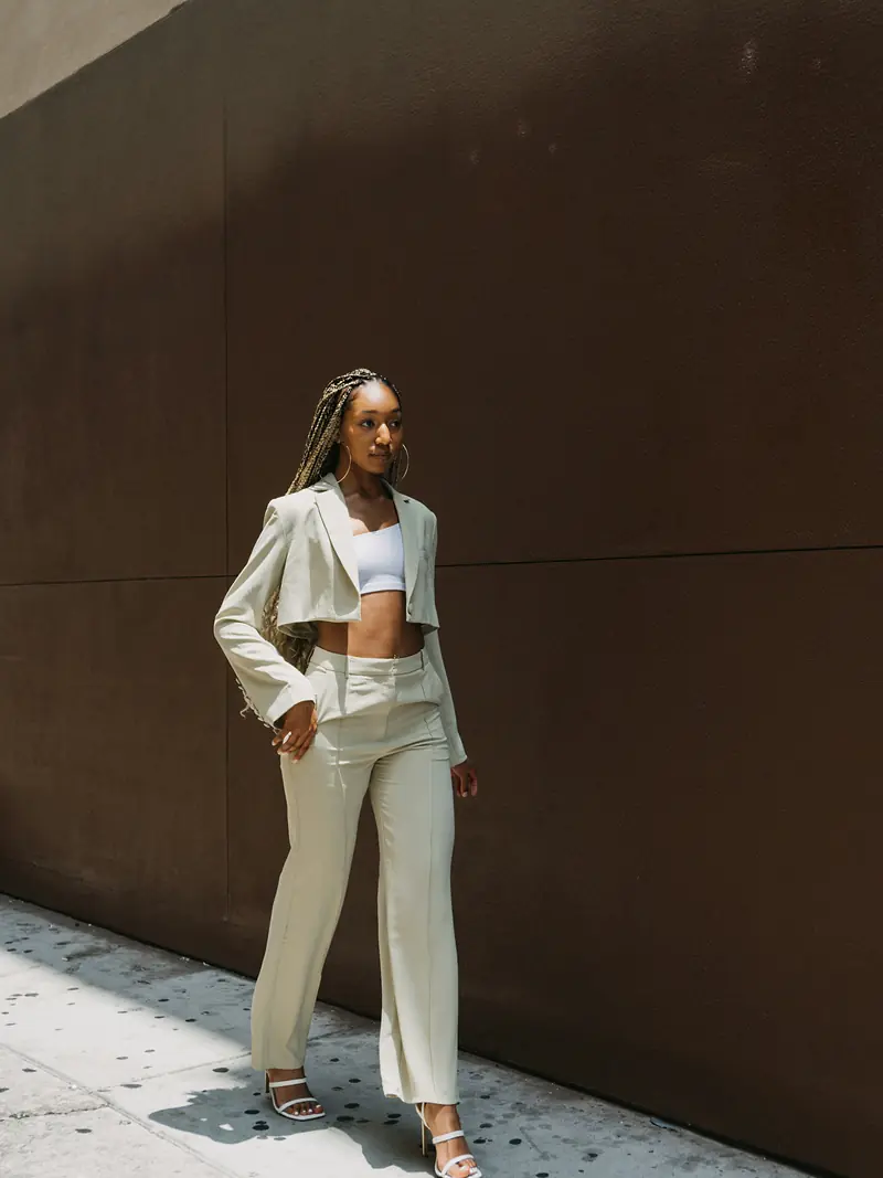 Cream cropped jacket and wide trousers against a dark wall